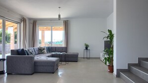 Ein modernes Wohnzimmer mit einem grauen Ecksofa, einem kleinen Tisch und einer Topfpflanze.