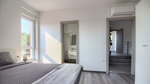 Ein Schlafzimmer mit Bett, Fenster, Badezimmer und einer Treppe.