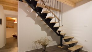 A modern staircase with wooden steps and black railings, leading to a room with a bed and a vase of dried plants. - Villa Antonici (Istria - Liznjan) (Liznjan)