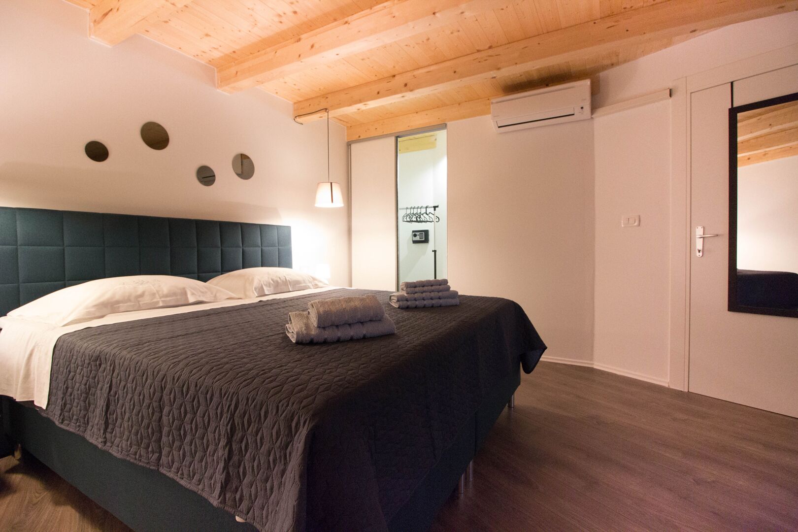 Un dormitorio con cama, mesita de noche, aire acondicionado de pared y una puerta.