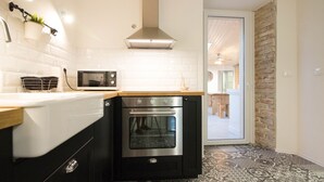 A compact kitchen with a microwave, oven, and a hanging plant. - Villa Antonici (Istria - Liznjan) (Liznjan)