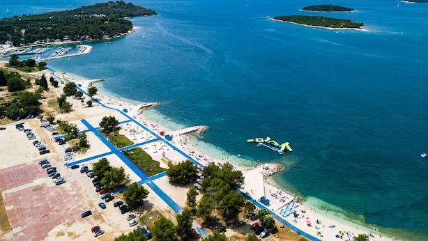 An aerial view of a coastal area with a beach, parking lots, and a marina. - Villa Rampic (Istria - Fažana) (Fažana)