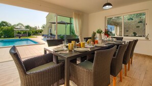 A dining area with a pool view, wicker furniture, and a table set for a meal. - Villa Rampic (Istria - Fažana) (Fažana)