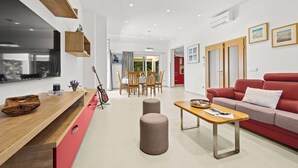A modern living room with a red sofa, a wooden coffee table, and a dining area with a wooden table and chairs. - Charming family villa with pool in Pula (Pula)