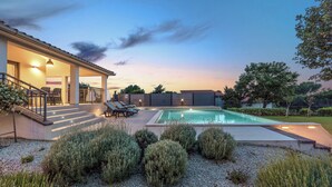 A swimming pool with a patio area, surrounded by gravel and shrubs. - Charming family villa with pool in Pula (Pula)