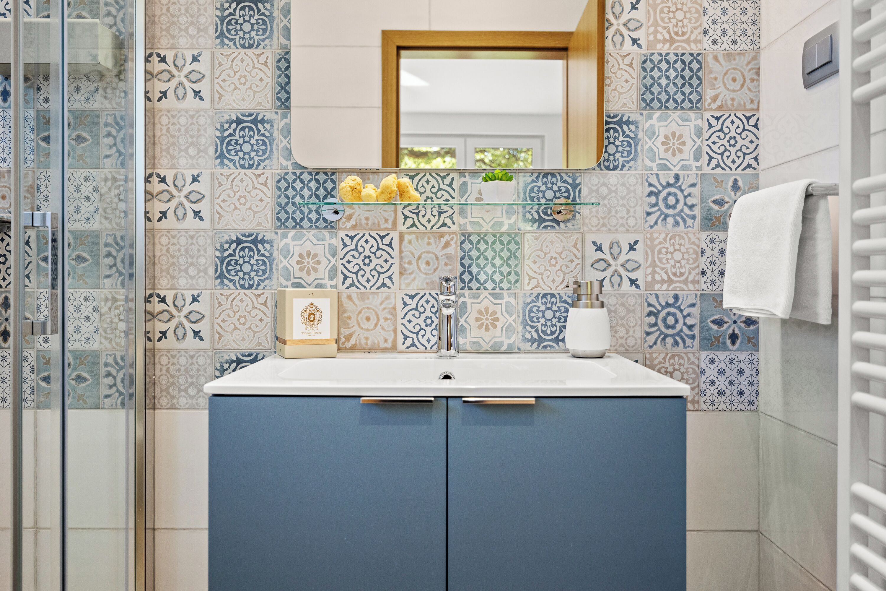 A bathroom with a tiled backsplash, a sink, and a mirror.