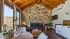 Un salon chaleureux avec un mur en pierre, un plafond en bois et une cuisine moderne.