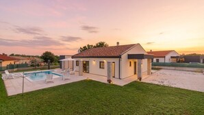 A modern house with a swimming pool, a patio, and a well-maintained lawn.