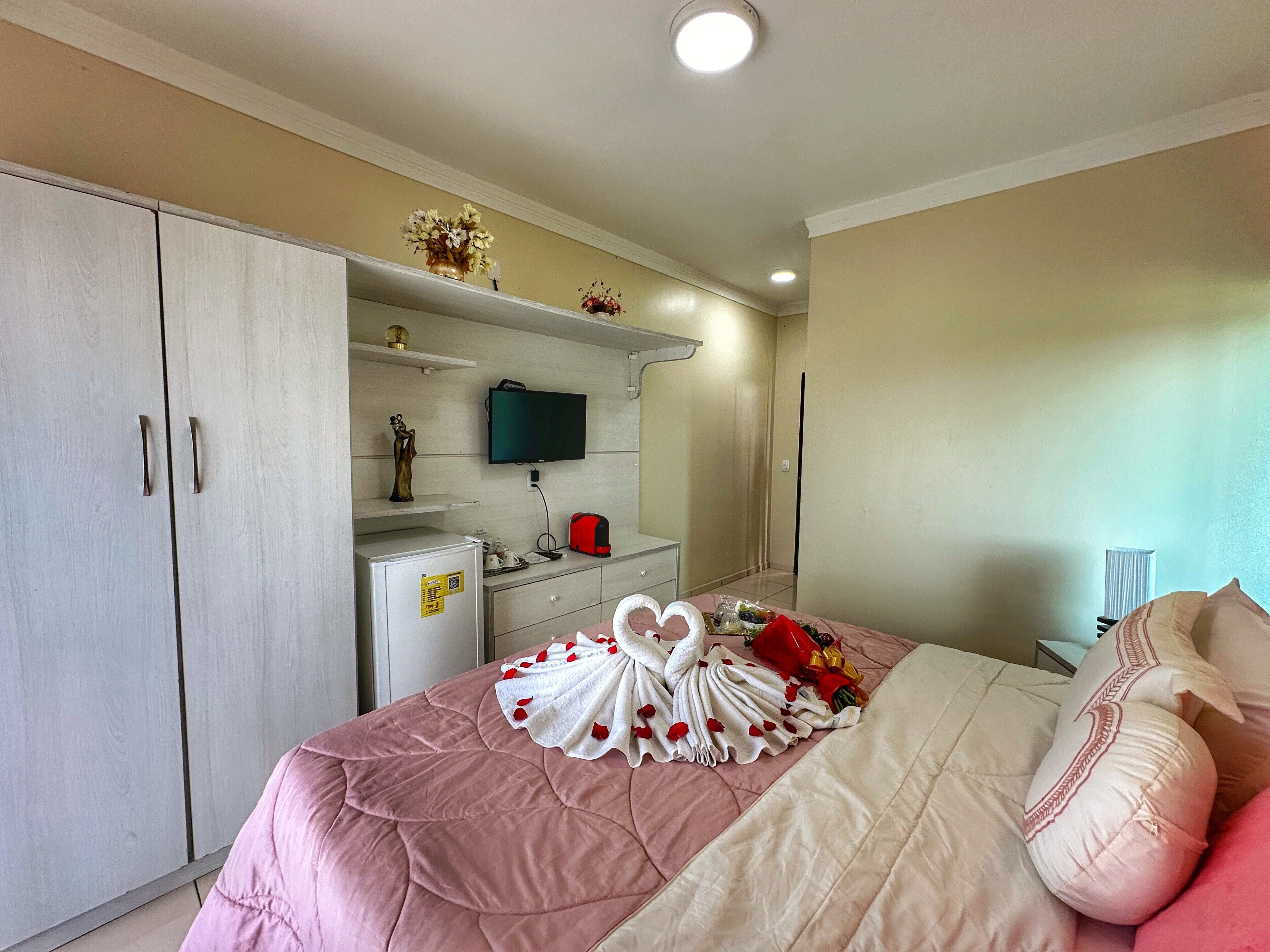 A hotel room with a bed, a dresser, a television, and a minibar.