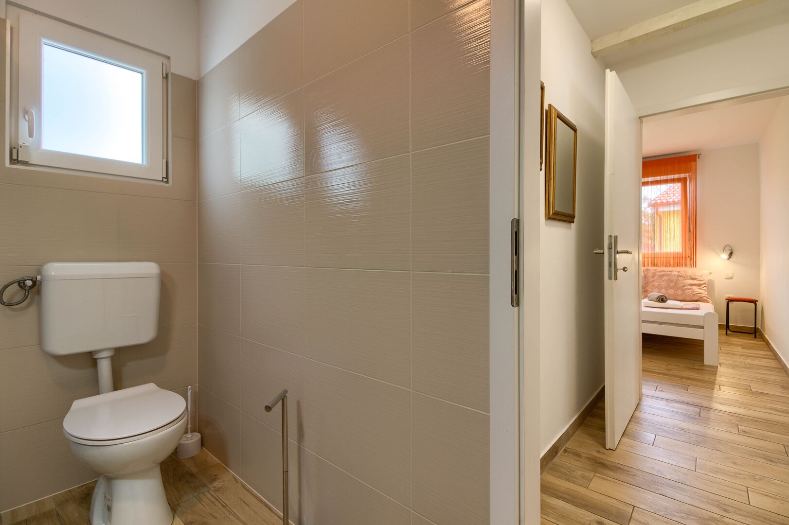 Une salle de bain moderne comprenant des toilettes, un espace douche et une petite table de chevet avec une chaise.