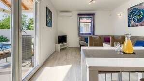 A modern living room with a TV, sofa, and dining area.