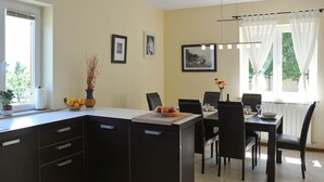 A modern kitchen with dark cabinetry, a central island, and a dining area with a table and chairs.