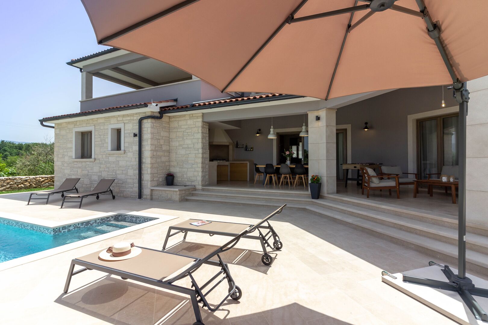Ein modernes Haus mit Swimmingpool, Sitzgelegenheiten im Freien und einer überdachten Terrasse.