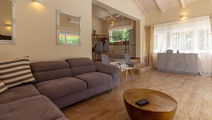 A modern living room with a sofa, a coffee table, and a dining area with chairs and a table.