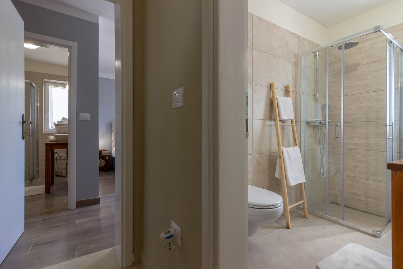 Une salle de bain moderne avec une douche à parois de verre, une échelle en bois et des toilettes.