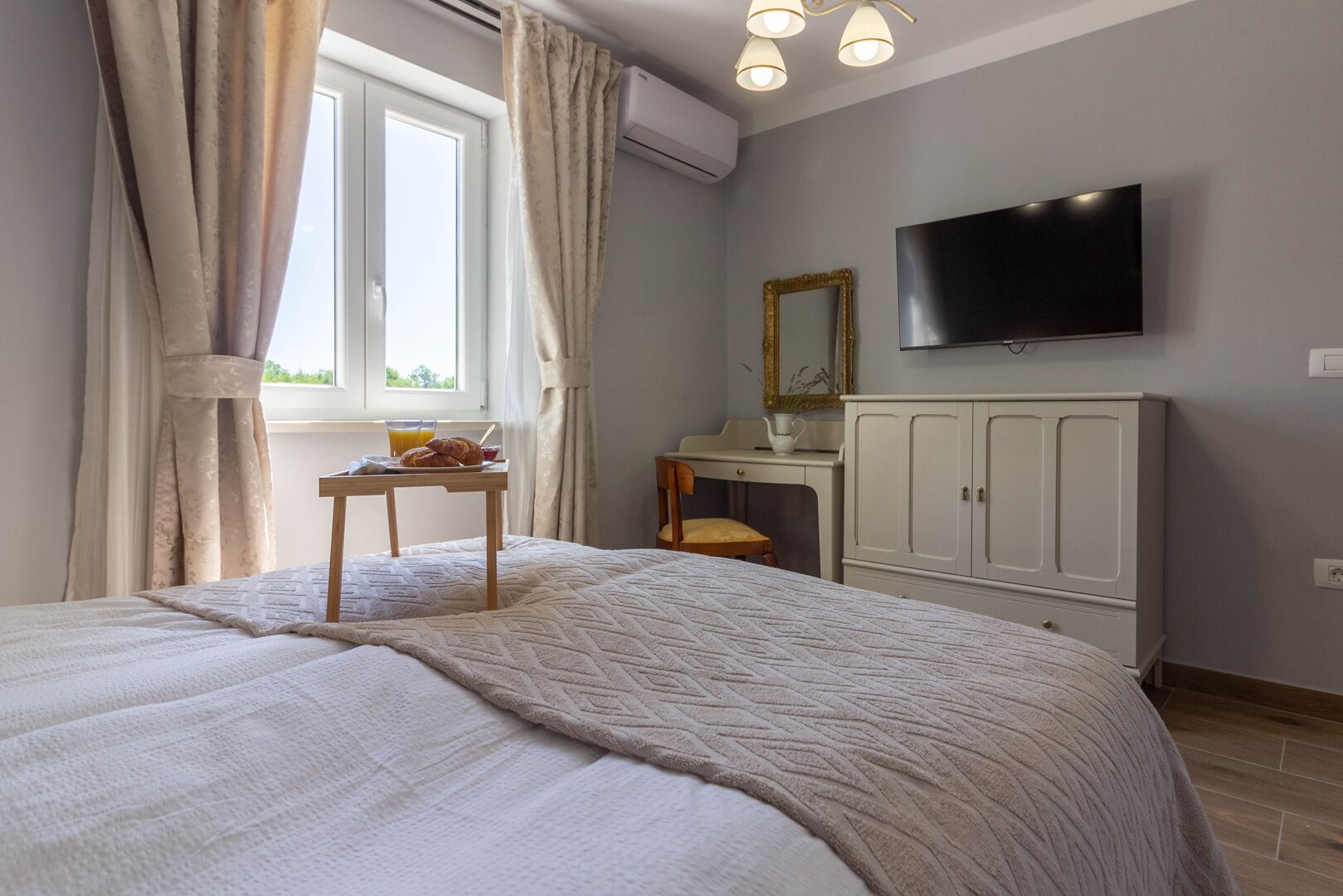 Un dormitorio con cama, una mesita de noche con provisions para el desayuno, un televisor y un armario.
