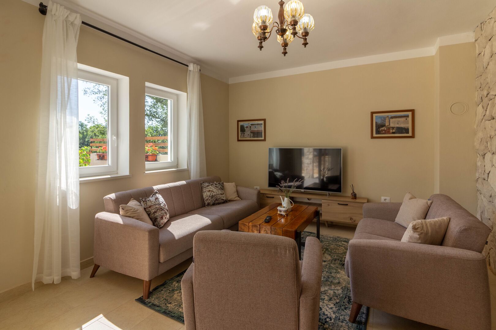 A living room with two sofas, a coffee table, a TV, and a stone wall.