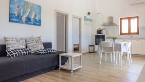 Uma sala de estar moderna com um sofá cinzento, uma mesinha e um quadro de veleiros.