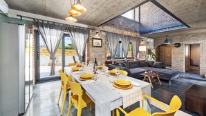 A spacious living area with a dining table set for a meal, a sofa, and a large window with a view. - Villa Baraka in Rovinj for rent | WiiBuk (Rovinj)