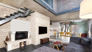 A modern living room with a fireplace, a flat-screen TV, a sofa, and a dining area with yellow chairs. - Villa Baraka in Rovinj for rent | WiiBuk (Rovinj)