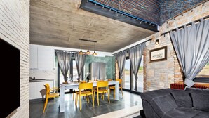 A modern dining area with a large table, yellow chairs, and a black sofa. - Villa Baraka in Rovinj for rent | WiiBuk (Rovinj)