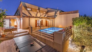 Een modern huis met een zwembad, buitenzitplaatsen en een overdekt terras.