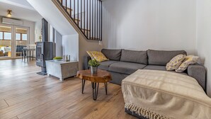 Een moderne woonkamer met een trap, een grijze bank, een houten salontafel en een open haard.