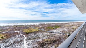 Un paysage côtier avec un pont en béton, une plage de sable et une végétation clairsemée.