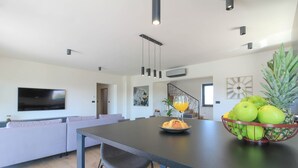 A modern kitchen with a dining table, chairs, and a fruit bowl. - Villa Esire (Istria - Pula) (Pula)