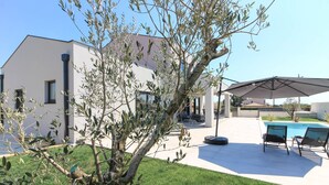 A modern house with a swimming pool, outdoor seating, and a tree in the foreground. - Villa Esire (Istria - Pula) (Pula)