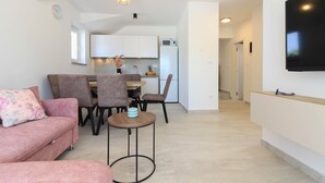 A modern living room with a pink sofa, a round coffee table, and a dining area with chairs and a table. - Villa Sunshine (Istria - Peroj) (Peroj)