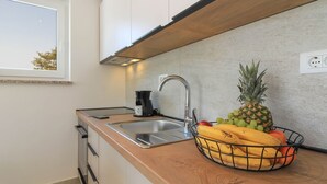 A kitchen with a stainless steel sink, a coffee maker, and a fruit basket containing bananas, oranges, and a pineapple. - Villa Sunshine (Istria - Peroj) (Peroj)