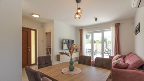 A dining area with a wooden table, chairs, a vase with dried plants, and a ceiling light fixture. - Villa Sunshine (Istria - Peroj) (Peroj)