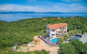 A two-story house with a red-tiled roof, a swimming pool, and a view of a lake. - Apartment Lara I (Istria - Labin) (Labin)