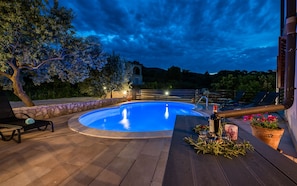 A swimming pool with a stone border, surrounded by lounge chairs and potted plants. - Apartment Lara I (Istria - Labin) (Labin)