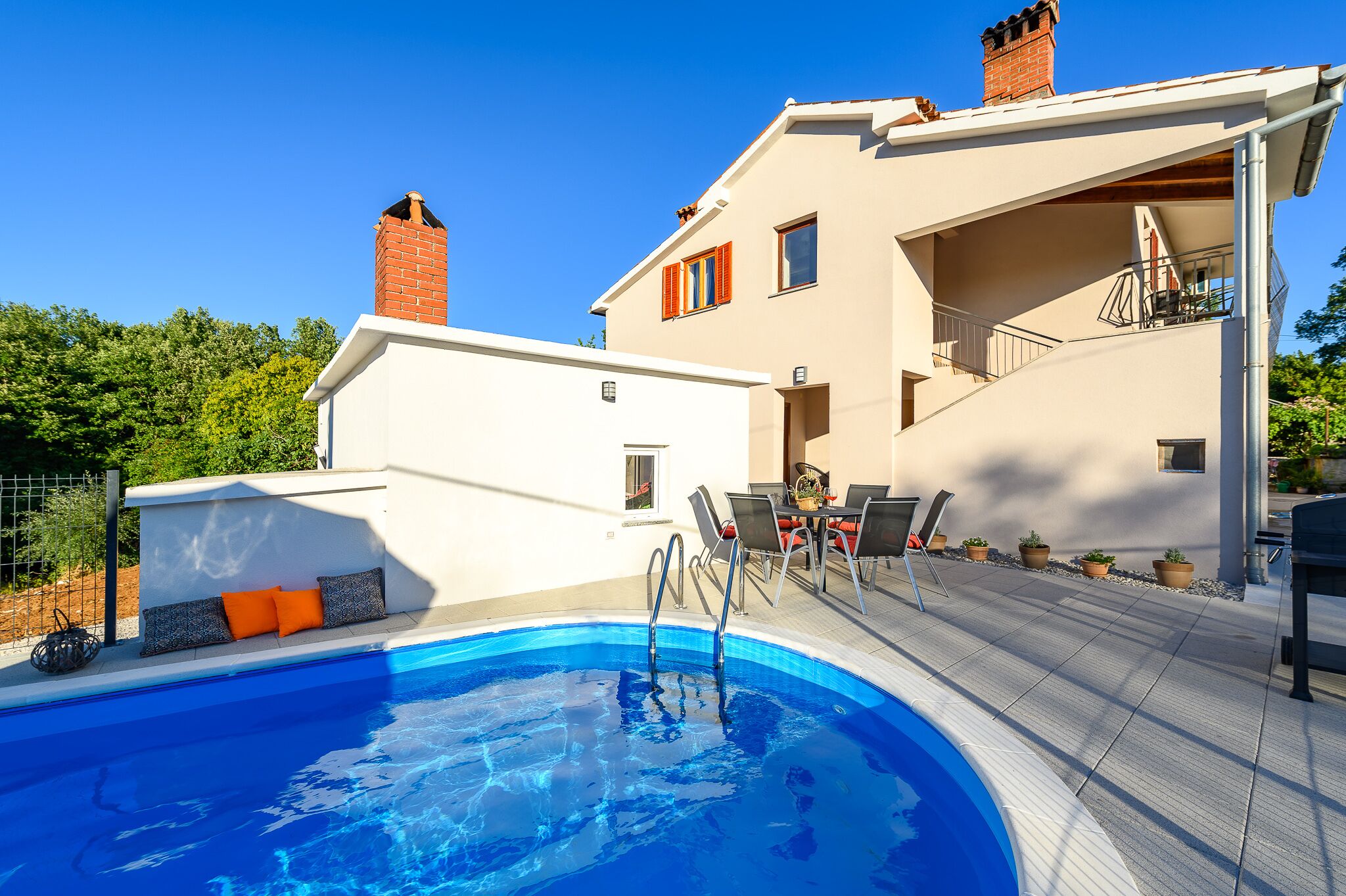 A modern house with a swimming pool, outdoor seating, and a balcony.