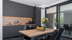Una cocina moderna con armarios oscuros, una mesa de comedor de madera y una cesta de frutas.