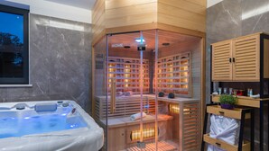 Un spa moderno con bañera de hidromasaje, estantes de madera con toallas y un baño de vapor con paredes de vidrio.