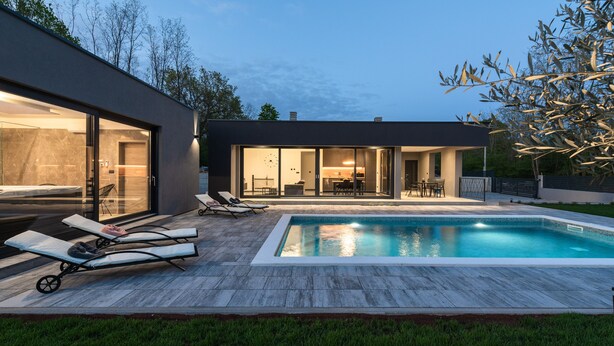 Una casa moderna con piscina, sillas de descanso y comedor.