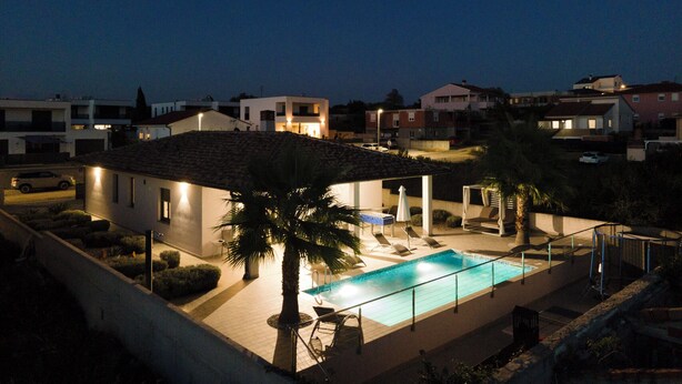 A residential area with a swimming pool, palm trees, and houses.