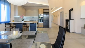A modern kitchen with a central island, a dining area with a glass table, and a living space with a fireplace.