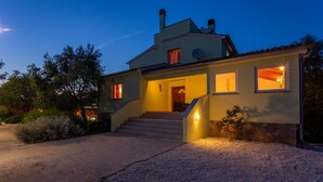 A two-story house with a stone foundation, a front porch, and a driveway leading to the entrance. - Villa VERSOVICA (Istria - Peruški) (Peruški)