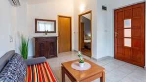 A living room with a sofa, a wooden cabinet, a table with a plant, and a large wooden door. - Villa VERSOVICA (Istria - Peruški) (Peruški)