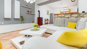 A modern living room with a white sofa, yellow cushions, a white coffee table, and a stone fireplace.