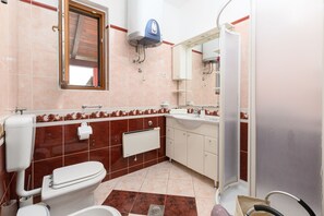 Un baño con inodoro, lavabo y ducha.