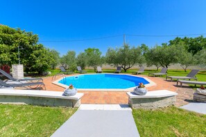 Una piscina con sillas de descanso y un camino de piedra que la lleva a ella.
