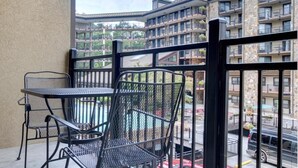 A balcony with a table and chairs, overlooking a multi-story building with balconies and a parking area. - Gatlinburg Ski Week! 2 Bedroom 2 Bath Full Kitchen Sleeps N6834 (Gatlinburg)