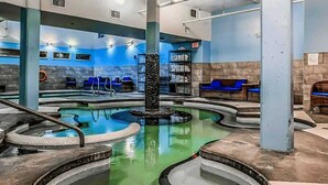 A spa area with a central hot tub, seating areas, and a reception desk. - Vista Peak Hydeaway at Solara Resort (Canmore)