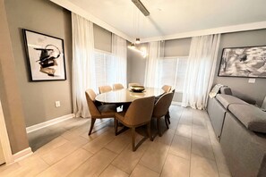 A dining area with a round table, six chairs, and a sofa.