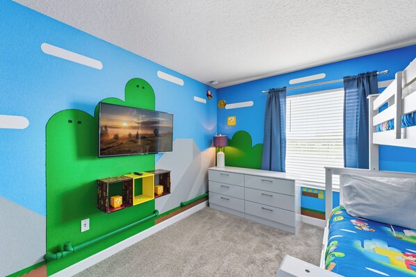 A child's bedroom with a bunk bed, a TV mounted on the wall, and a window with curtains.